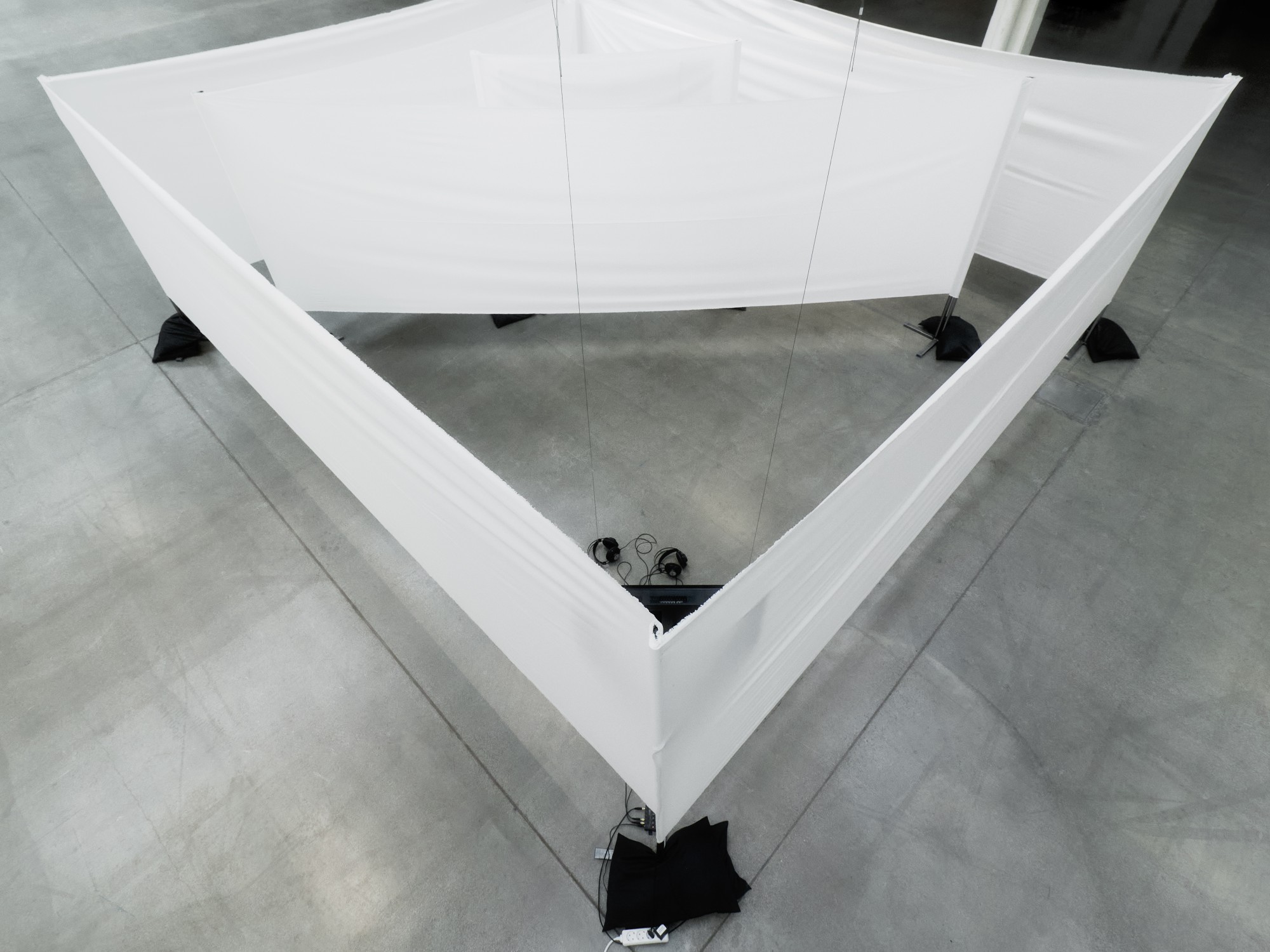 A corner of the labyrinth seen from above, with two pairs of headphones on the floor inside it.